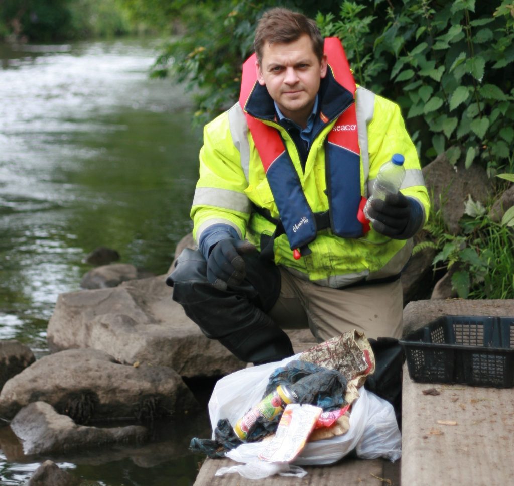 Pete sitting by river with collected litter