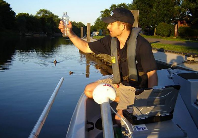 APEM staff member collecting a water sample